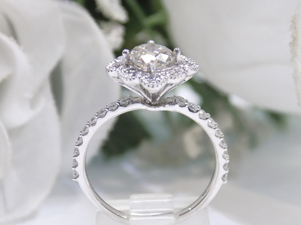 This is a 1.25ct total weight natural diamond ring with a .84ct natural round brilliant diamond in the center in white gold shown on a flowery white gold.