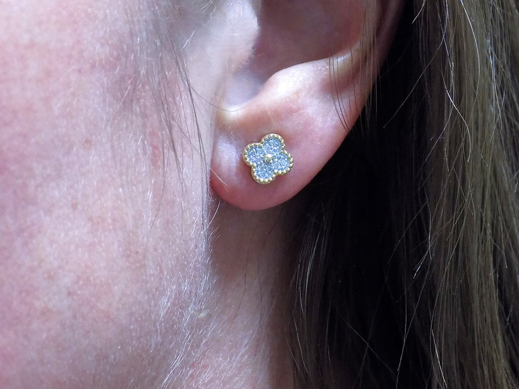 This is a pair of earrings in Van Cleef style with natural diamonds win 2 tone white and yellow gold in a womans ear.