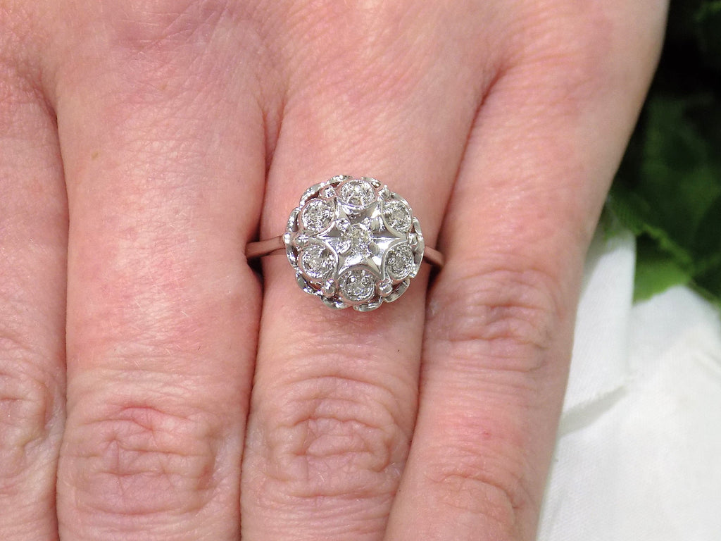 This is a 7 stone .10ct Total Weight Natural Diamond Vintage Ring in 14K White Gold on a ladies finger.