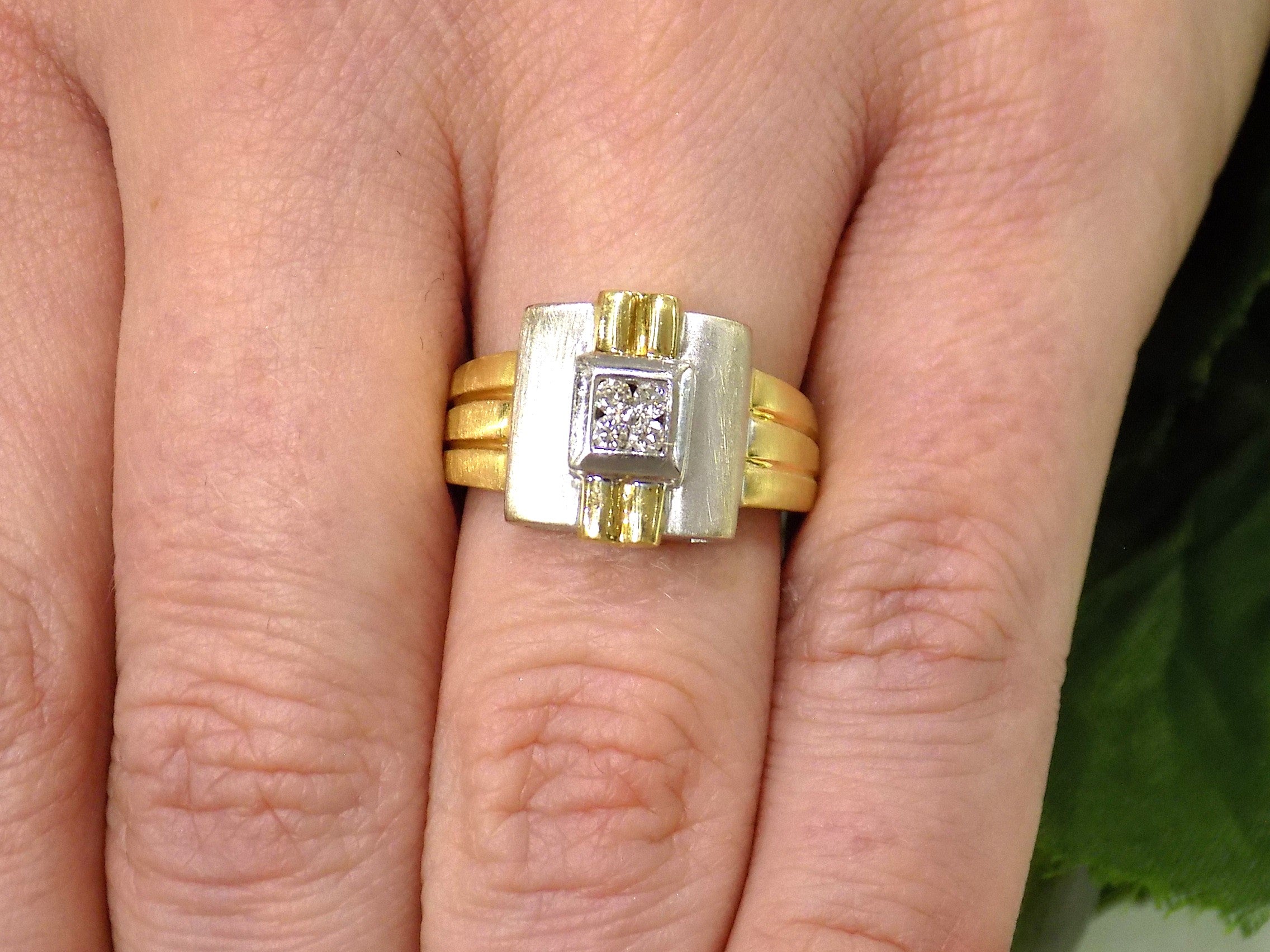This is a woman's vintage art-deco ring that is two-tone with a brushed 18K yellow and white gold finish with .20ct total diamond weight on a women's finger.