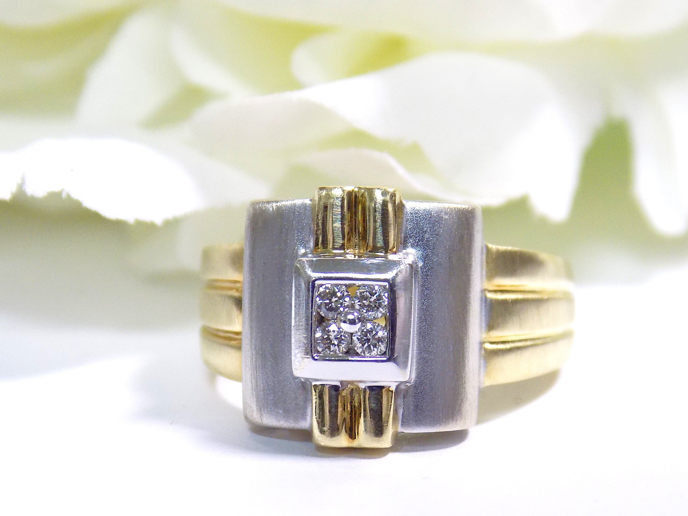 This is a woman's vintage art-deco ring that is two-tone with a brushed 18K yellow and white gold finish with .20ct total diamond weight with a floral background.