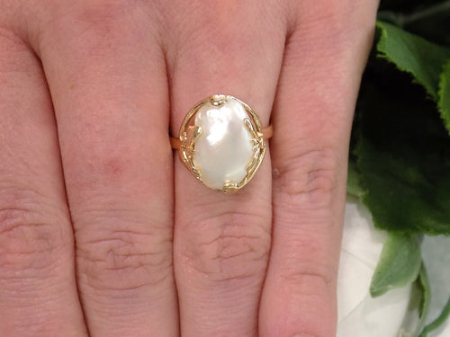 This is a genuine freshwater pearl ring in yellow gold shown on a woman's finger.