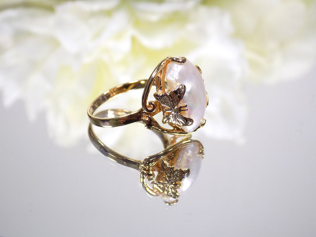 This is a genuine freshwater pearl ring in yellow gold on white mirrored background. 