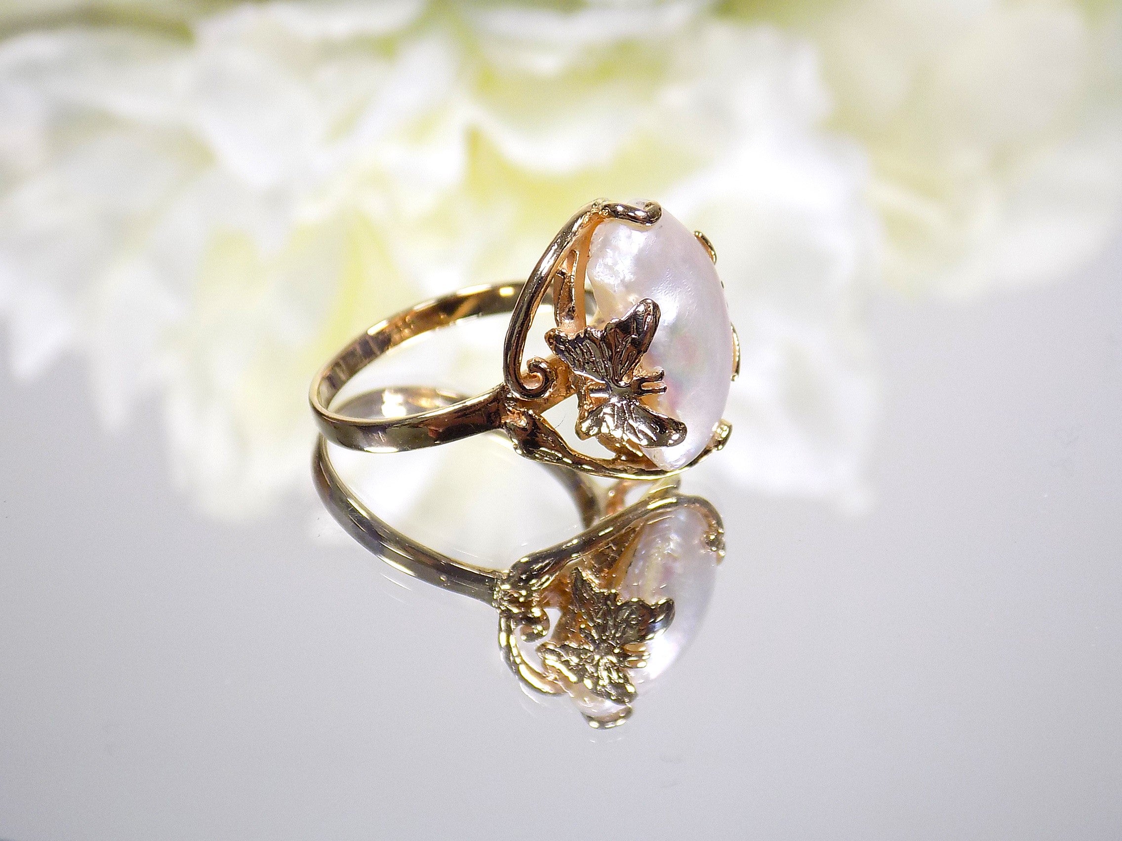 This is a genuine freshwater pearl ring in yellow gold on white mirrored background. 