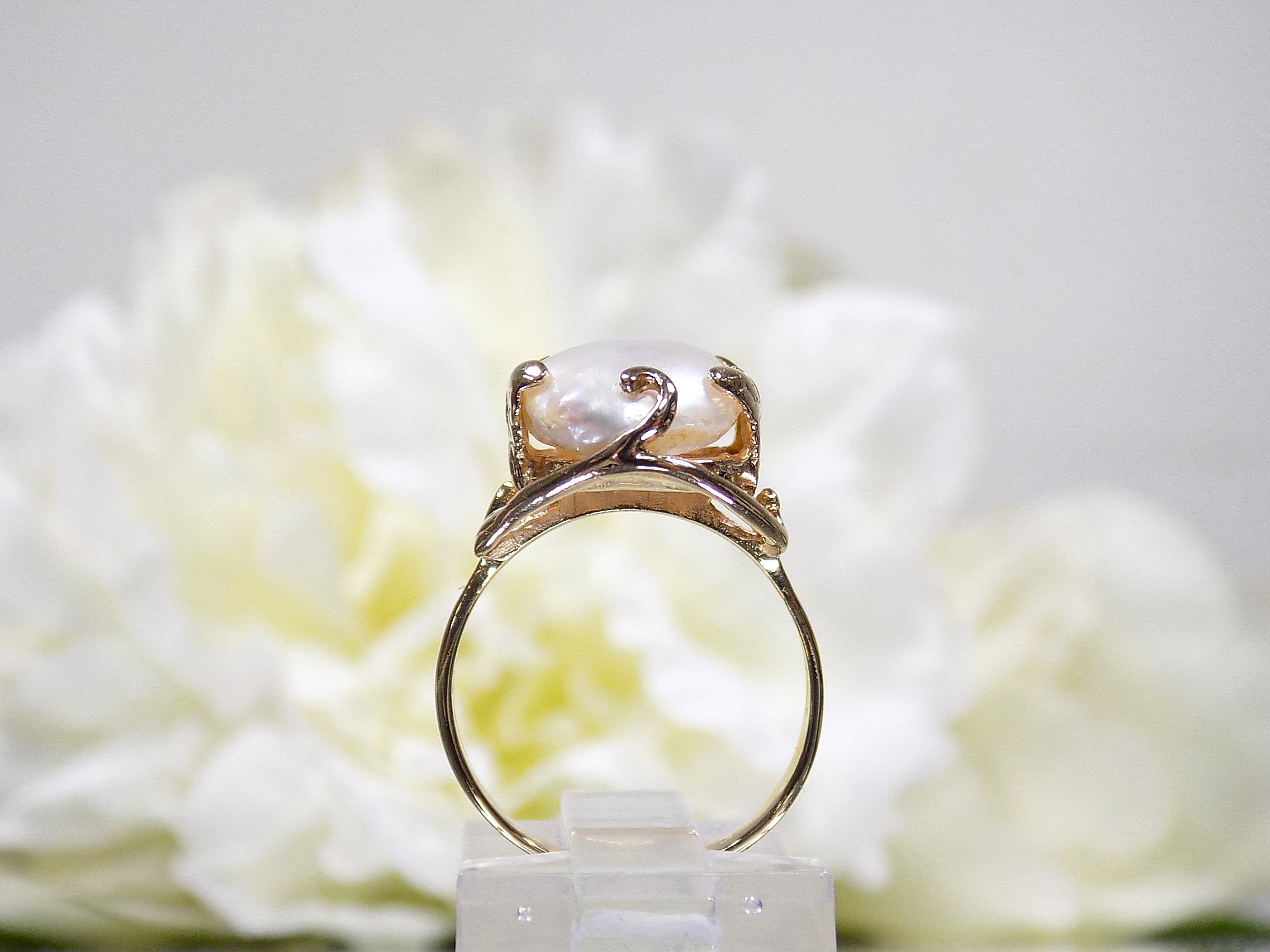 This is a side view of a genuine freshwater pearl ring in yellow gold shown on white background.