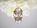 This is a genuine freshwater pearl ring in yellow gold on white mirrored background. 