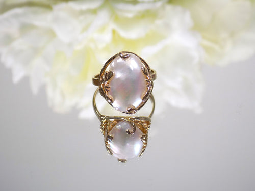 This is a genuine freshwater pearl ring in yellow gold on white mirrored background. 