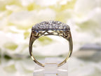 This is a side view of a women's ring called a "princess" style ring usually passed down from mother to daughter throughout the generations.  It a yellow gold ring with diamonds mounted in white gold in the top and has a white flowery background.