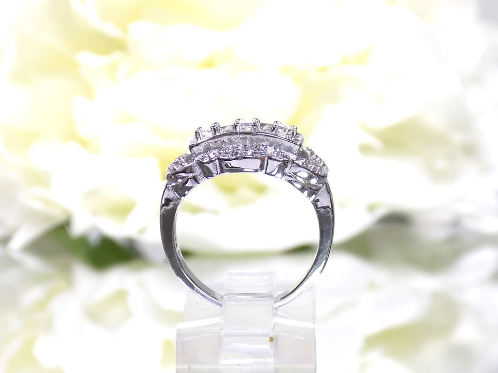 This is a vintage variation of the princess style women's ring with 3 primary diamond in the center with a total weight of .25ct in 14K white gold with a white background in a side view.