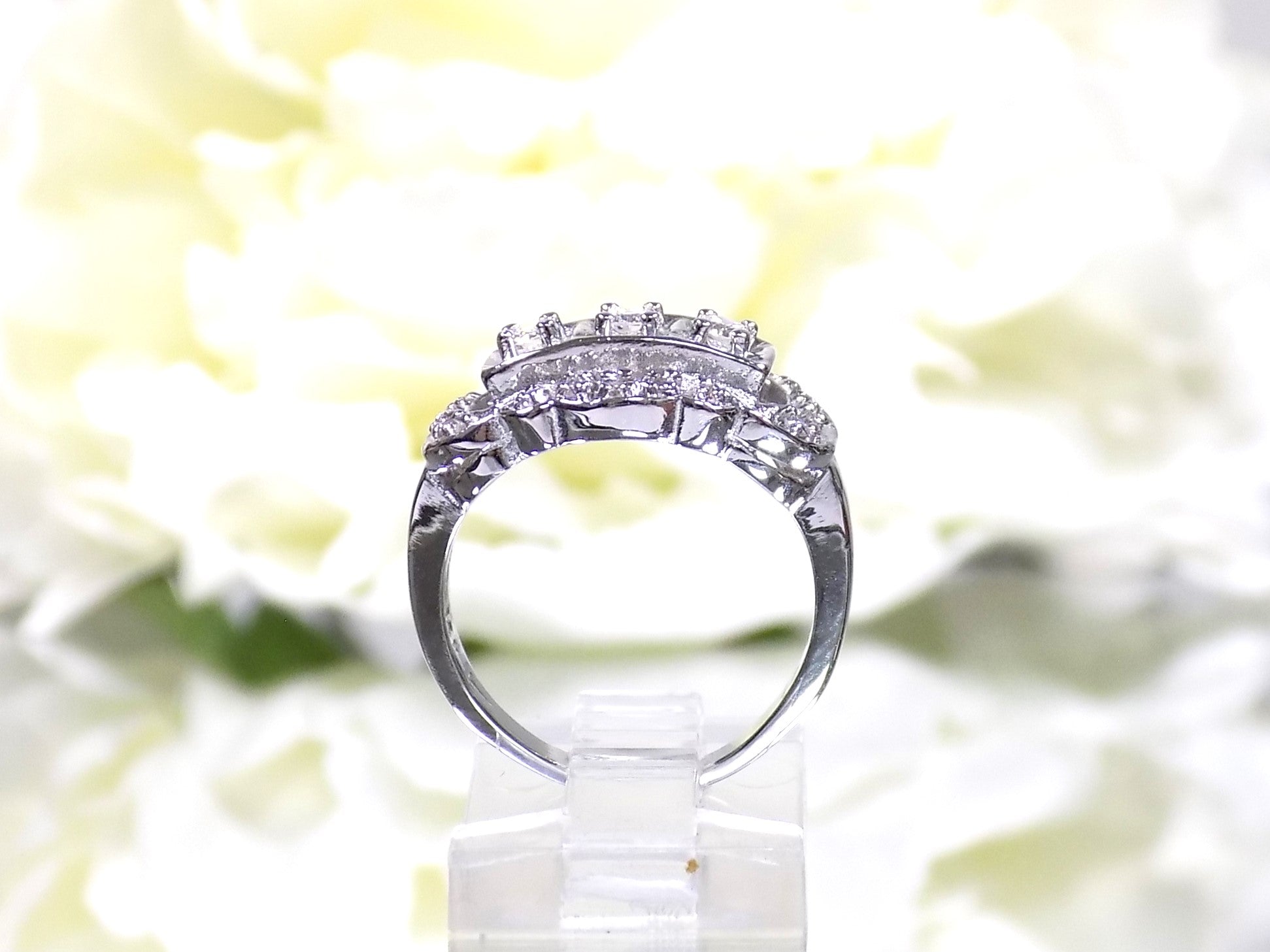 This is a vintage variation of the princess style women's ring with 3 primary diamond in the center with a total weight of .25ct in 14K white gold with a white background in a side view.