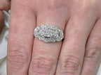 This is a vintage variation of the princess style women's ring with 3 primary diamond in the center with a total weight of .25ct in 14K white gold on a women's finger.