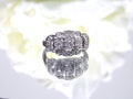 This is a vintage variation of the princess style women's ring with 3 primary diamond in the center with a total weight of .25ct in 14K white gold with a white background.