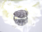 This is a vintage variation of the princess style women's ring with 3 primary diamond in the center with a total weight of .25ct in 14K white gold with a white background.