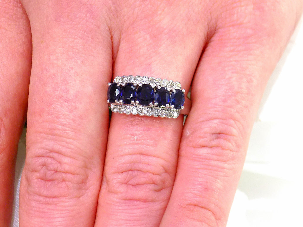 This is a women's vintage estate ring with a total of 2.00ct in natural oval sapphires and round diamonds in 14K white gold on a women's finger.