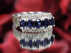 This is a women's vintage estate ring with a total of 2.00ct in natural oval sapphires and round diamonds in 14K white gold on a mirrored surface with a red floral background.