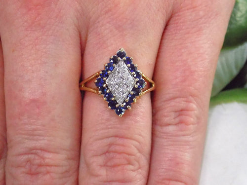 This is a refurbished vintage genuine sapphire & diamond cluster ring in yellow gold shown on a women's finger.