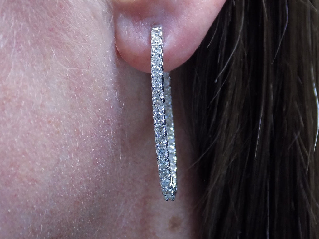 2.00ct total weight natural diamond in and out style oval hoops in 14K white gold in a ladies ear.