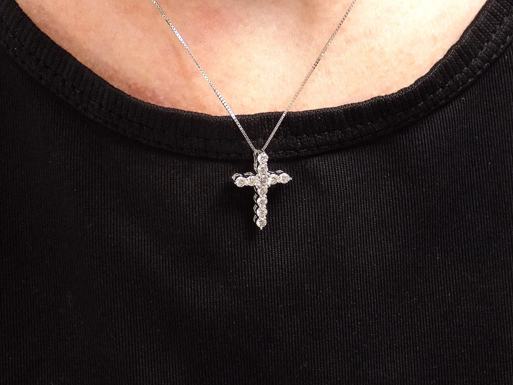 This is a .50ct natural diamond cross pendant in 14K white gold on a ladies neck with a black shirt.
