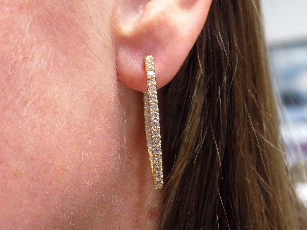 2.00ct total weight natural diamond in and out style oval hoops in 14K yellow gold in a ladies ear.
